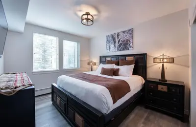 a bedroom with a large bed and two windows at Deluxe Fraser Crossing Founders Pointe Condo with Ski Storage and washer dryer condo in Winter Park