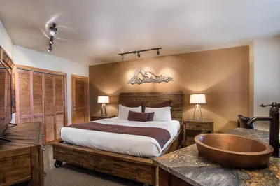 a bedroom with a large bed and a bath tub at Stunning Zephyr Mountain Lodge Condo Overlooking The Village Plaza condo in Winter Park