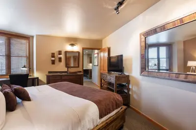 a bedroom with a large bed and a mirror at Stunning Zephyr Mountain Lodge Condo Overlooking The Village Plaza condo in Winter Park
