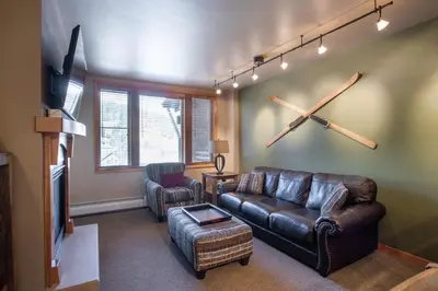 a living room with a leather couch and a tv at Stunning Zephyr Mountain Lodge Condo Overlooking The Village Plaza condo in Winter Park