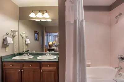 a bathroom with two sinks and a tub and a mirror at Lovely Zephyr Mountain Lodge Condo with Mountain Slope Views condo in Winter Park