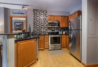 a kitchen with wooden cabinets and a stainless steel refrigerator at Lovely Zephyr Mountain Lodge Condo with Mountain Slope Views condo in Winter Park