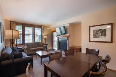 a living room with a table and chairs and a living room with a television at Lovely Zephyr Mountain Lodge condo with Continental Divide and Village Views condo in Winter Park
