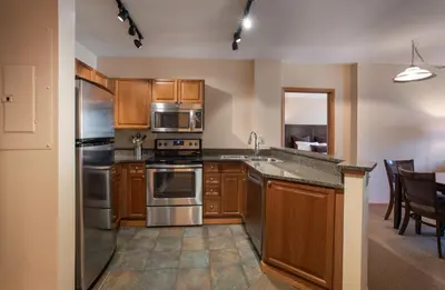 a kitchen with wooden cabinets and stainless steel appliances at Lovely Zephyr Mountain Lodge condo with Continental Divide and Village Views condo in Winter Park
