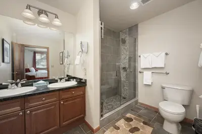 a bathroom with a shower and two sinks and a toilet at Terrific Zephyr Mountain Lodge Condo With Beautiful Views of the Continental Divide near Mountain condo in Winter Park