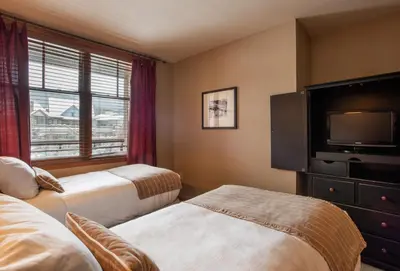 a hotel room with two beds and a flat screen tv at Large Zephyr Mountain Lodge condo with fireplace and Village Views condo in Winter Park