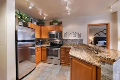 a kitchen with wooden cabinets and stainless steel appliances at Great Zephyr Mountain Lodge Condo with Village & Continental Divide Views condo in Winter Park