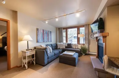 a living room with a blue couch and a tv at Great Zephyr Mountain Lodge Condo with Village & Continental Divide Views condo in Winter Park