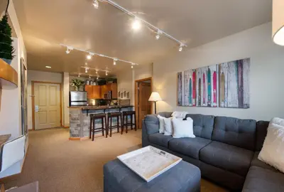 a living room with a couch and a kitchen at Great Zephyr Mountain Lodge Condo with Village & Continental Divide Views condo in Winter Park
