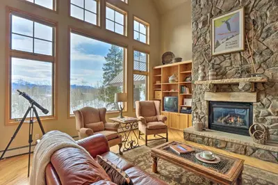 a living room with a large stone fireplace at Grand Fraser Escape with Private Deck and Hot Tub in Fraser