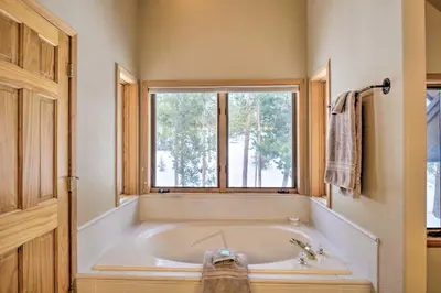 a large white tub in a bathroom with a window at Grand Fraser Escape with Private Deck and Hot Tub in Fraser