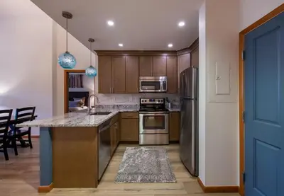 a kitchen with wooden cabinets and stainless steel appliances at Zephyr Mountain Lodge - Premium Rated Condo 1701 in Winter Park