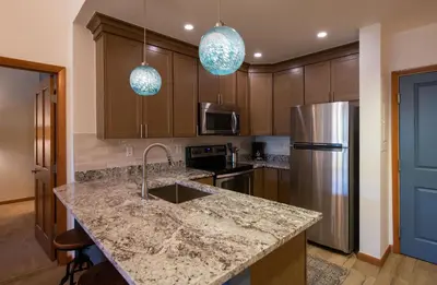 a kitchen with a granite counter top and a refrigerator at Zephyr Mountain Lodge - Premium Rated Condo 1701 in Winter Park