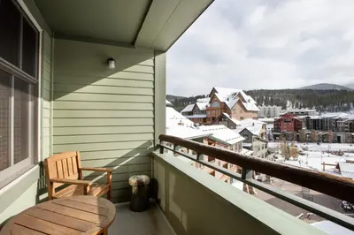 a balcony with a wooden chair and a view of a town at Upgraded Zephyr Mountain Lodge Condo with Continental Divide Views Close to Mountain condo in Winter Park