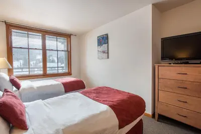 a bedroom with two beds and a flat screen tv at Upgraded Zephyr Mountain Lodge Condo with Continental Divide Views Close to Mountain condo in Winter Park
