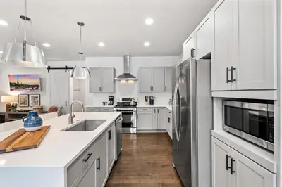 a kitchen with white cabinets and a stainless steel refrigerator at Steps from River & Old Town - Hot Tub & King Bed in Fort Collins