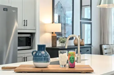 a kitchen counter with a blue vase and glasses on a cutting board at Steps from River & Old Town - Hot Tub & King Bed in Fort Collins