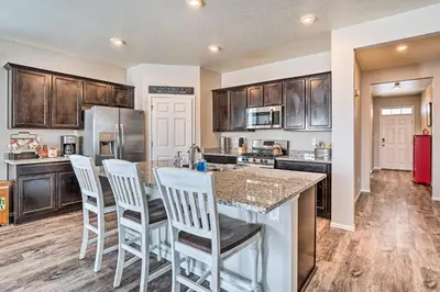 a kitchen with wooden cabinets and a island with bar stools at Dreamy Windsor Home with Grill about 3 Miles to Lake! in Windsor