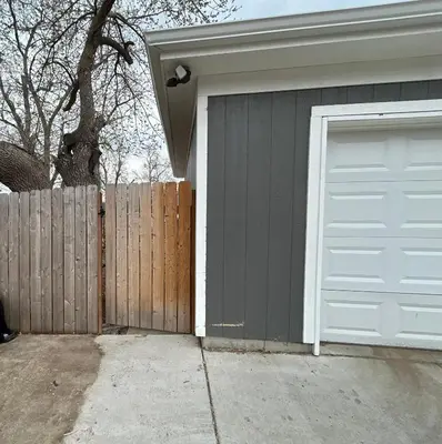a garage with a white garage door next to a fence at Basement Unit 2br 2ba in Barnum West Near Belmar and Sloan Lake 10 mins to Downtown in Denver