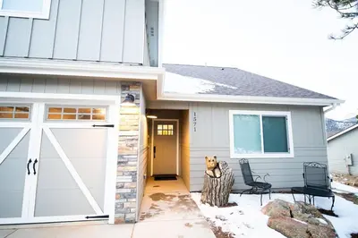 a house with a white garage door and two chairs at The Getaway,Hot Tub, AC, 2miles from RMNP in Estes Park