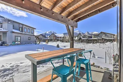 a table and two chairs on a deck with a snow covered yard at Hike, Ski, Golf, and Fish Silverthorne Townhome! in Silverthorne