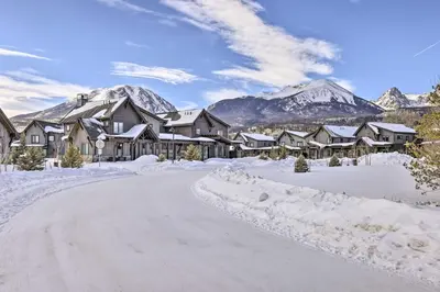 a snow covered road with houses and mountains in the background at Hike, Ski, Golf, and Fish Silverthorne Townhome! in Silverthorne