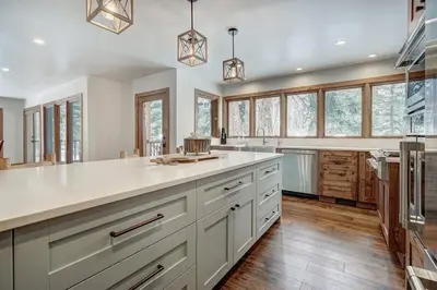 a large kitchen with white cabinets and wooden floors at Sunset Cabin - Creekside by Ski Country Resorts in Frisco