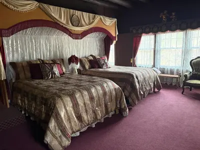 a bedroom with two beds and a chair and windows at Inn of Glen Haven in Glen Haven