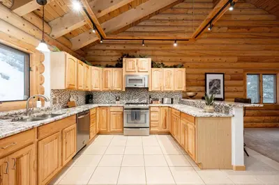 a kitchen with wooden cabinets and appliances in a cabin at Iconic Log Cabin Escape - Idaho Springs - Hot Tub in Idaho Springs