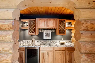 a kitchen with wooden cabinets and a log wall at Iconic Log Cabin Escape - Idaho Springs - Hot Tub in Idaho Springs