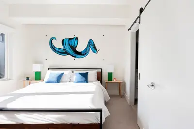 a bedroom with a bed with a blue sign on the wall at Art-Inspired Loft with Mountain View - Zuni Lofts in Denver