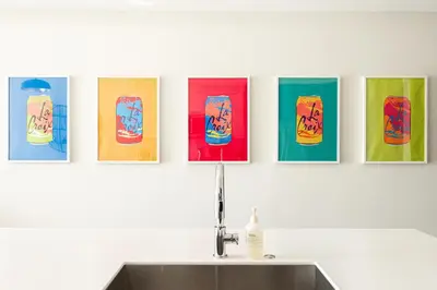 a row of four paintings on a wall above a sink at Art-Inspired Loft with Mountain View - Zuni Lofts in Denver