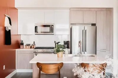 a kitchen with white cabinets and a stainless steel refrigerator at Gallery Retreat - Skyline Views - Zuni Lofts in Denver