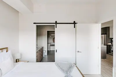 a bedroom with white walls and a bed with a chair at Contemporary Cool Lifestyle Loft - Zuni Lofts in Denver