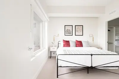 a white bedroom with a bed with red pillows at A Luxe Point of View - Pet-Friendly - Zuni Lofts in Denver