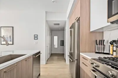 a kitchen with white walls and wooden cabinets at On Cloud 9 - Curated Lifestyle Loft - Zuni Lofts in Denver