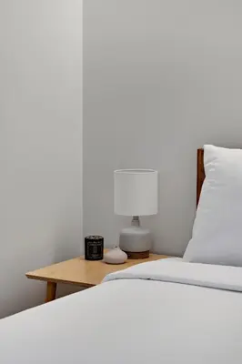 a bed with a lamp and a nightstand with a white bed at Modern Lifestyle Loft with View - Zuni Lofts in Denver