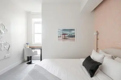 a white bedroom with a bed and a chair at Fifty Shapes of Modern - Skyline Loft - Zuni Lofts in Denver