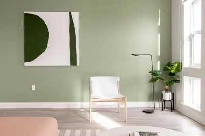 a living room with a white chair and a plant at Skyline Loft - Sweeping Views - Central LoHi in Denver