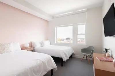 a white bedroom with two beds and a window at Skyline Loft - Sweeping Views - Central LoHi in Denver
