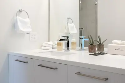 a white bathroom with a sink and a mirror at Skyline Loft - Sweeping Views - Central LoHi in Denver