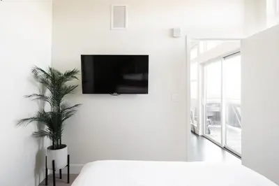 a white bedroom with a tv on the wall at New Spacious Modern Loft - Center of LoHi in Denver