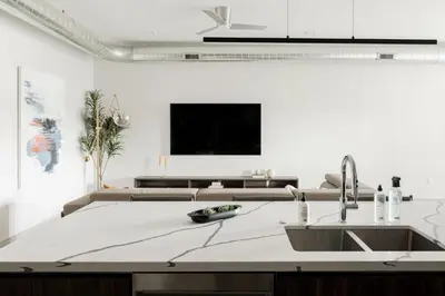 a kitchen with a sink and a tv on a wall at Walk to Gameday - Jefferson Park Condo - Tesoro in Denver