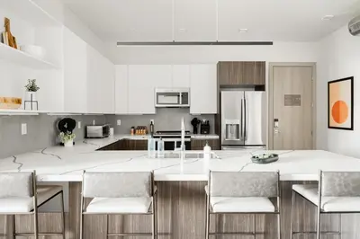 a kitchen with a large white island with chairs at Walk to Gameday - Jefferson Park Condo - Tesoro in Denver