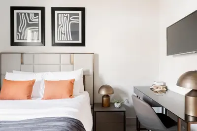 a bedroom with a bed with orange pillows and a desk at Walk to Gameday - Jefferson Park Condo - Tesoro in Denver