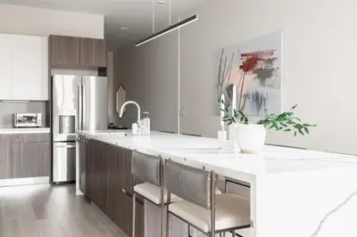 a kitchen with a large white counter and chairs at City Views! - Chic Jefferson Park Condo - Tesoro in Denver