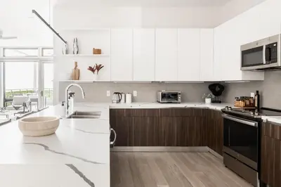 a white kitchen with white cabinets and a sink at Gameday Oasis - Private Balcony - Jefferson Park - Tesoro in Denver