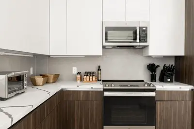 a kitchen with white cabinets and a stove and microwave at Luxurious Escape - Walk to Empower Field - Tesoro in Denver