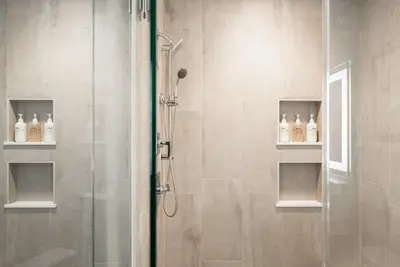 a shower with a glass door and bottles on shelves at Luxurious Escape - Walk to Empower Field - Tesoro in Denver