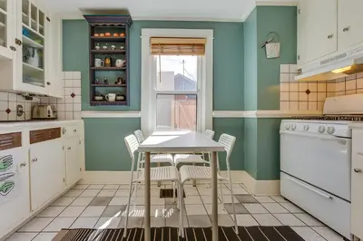 a kitchen with green walls and a table and chairs at 2 Mi to Washington Park Convenient Denver Home! in Denver